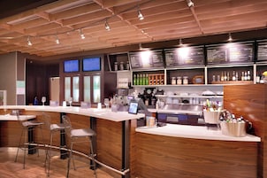 A modern bar area with a wooden counter, bar stools, and a menu board.