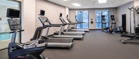 Un gimnasio con cintas de correr, elípticas y equipos de pesas.