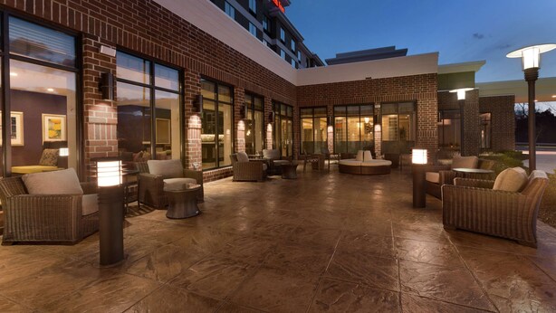A hotel courtyard with outdoor seating, large windows, and a brick facade. - Hilton Garden Inn Pittsburgh Airport South-Robinson Mall (Pittsburgh)