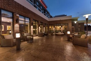 A hotel courtyard with outdoor seating, large windows, and a brick facade. - Hilton Garden Inn Pittsburgh Airport South-Robinson Mall (Pittsburgh)