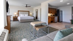 Habitación de hotel con cama, escritorio, silla, kitchenette y televisor.