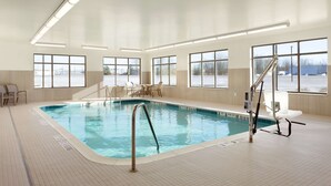 Una piscina interior con agua cristalina, rodeada de ventanas y un suelo de baldosas.