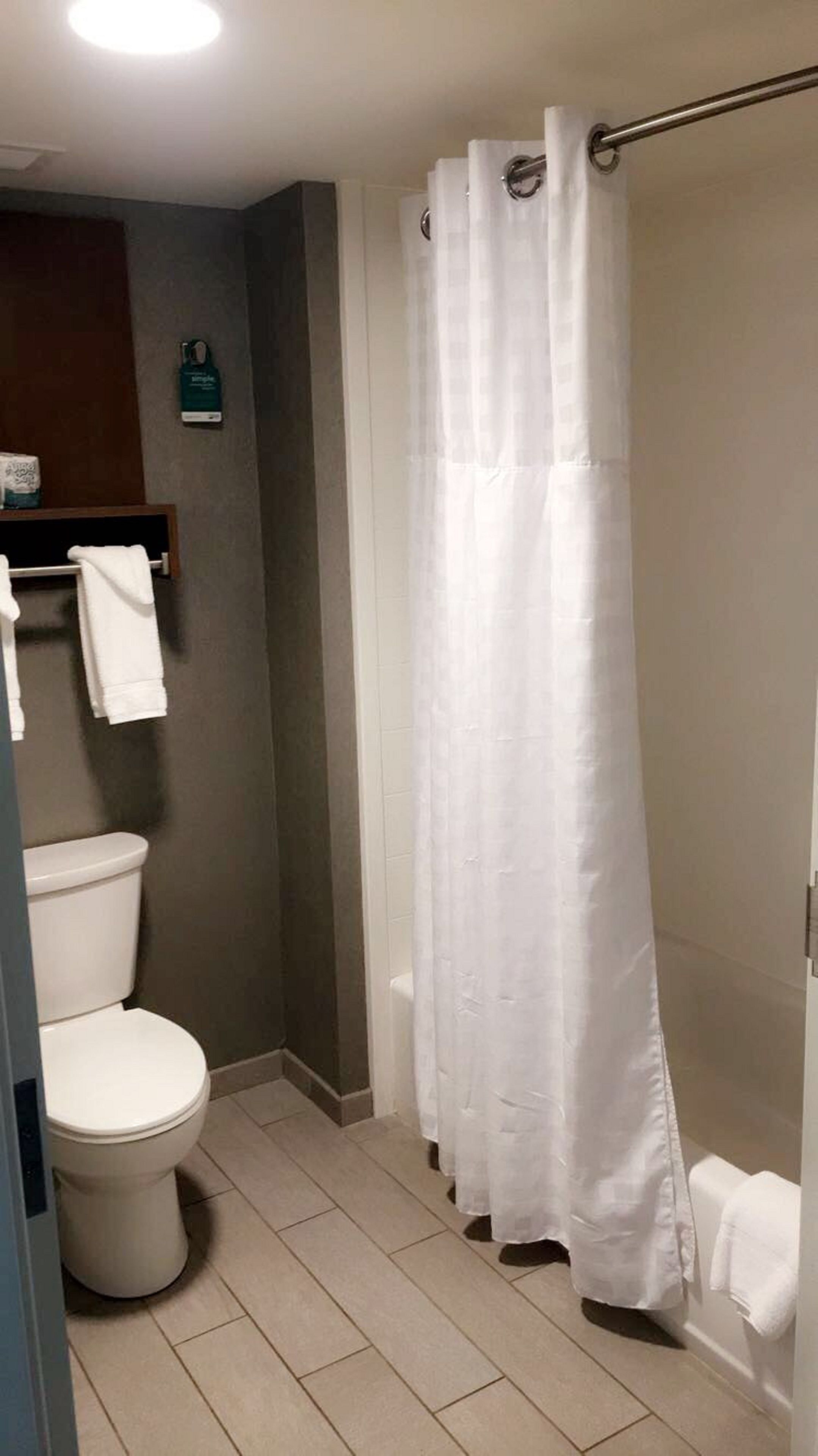 Une salle de bain équipée de toilettes, d’un rideau de douche et d’un porte-serviettes.