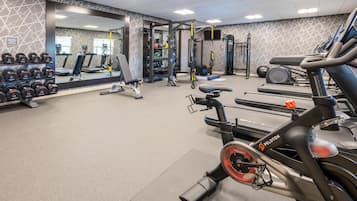Uma academia com esteiras, bicicletas ergométricas e aparelhos de musculação.