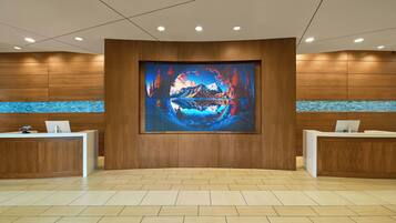 A reception area with two reception desks, a large digital artwork on the wall, and a herringbone patterned floor.
