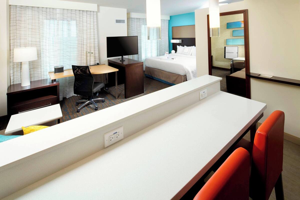 Habitación de hotel con escritorio, silla, cama y televisor.