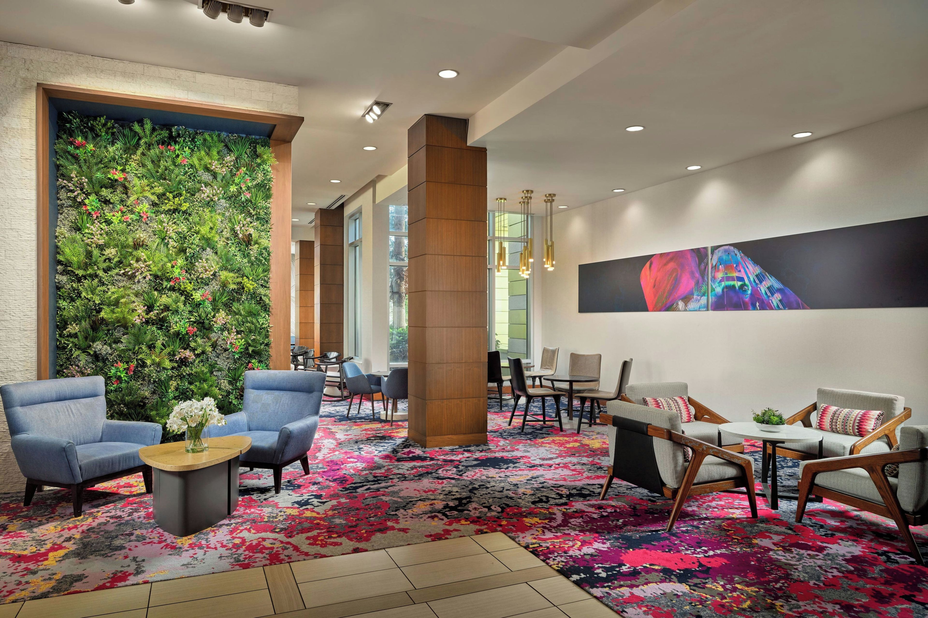 A hotel lobby with a vertical garden, seating area, and artwork on the wall.