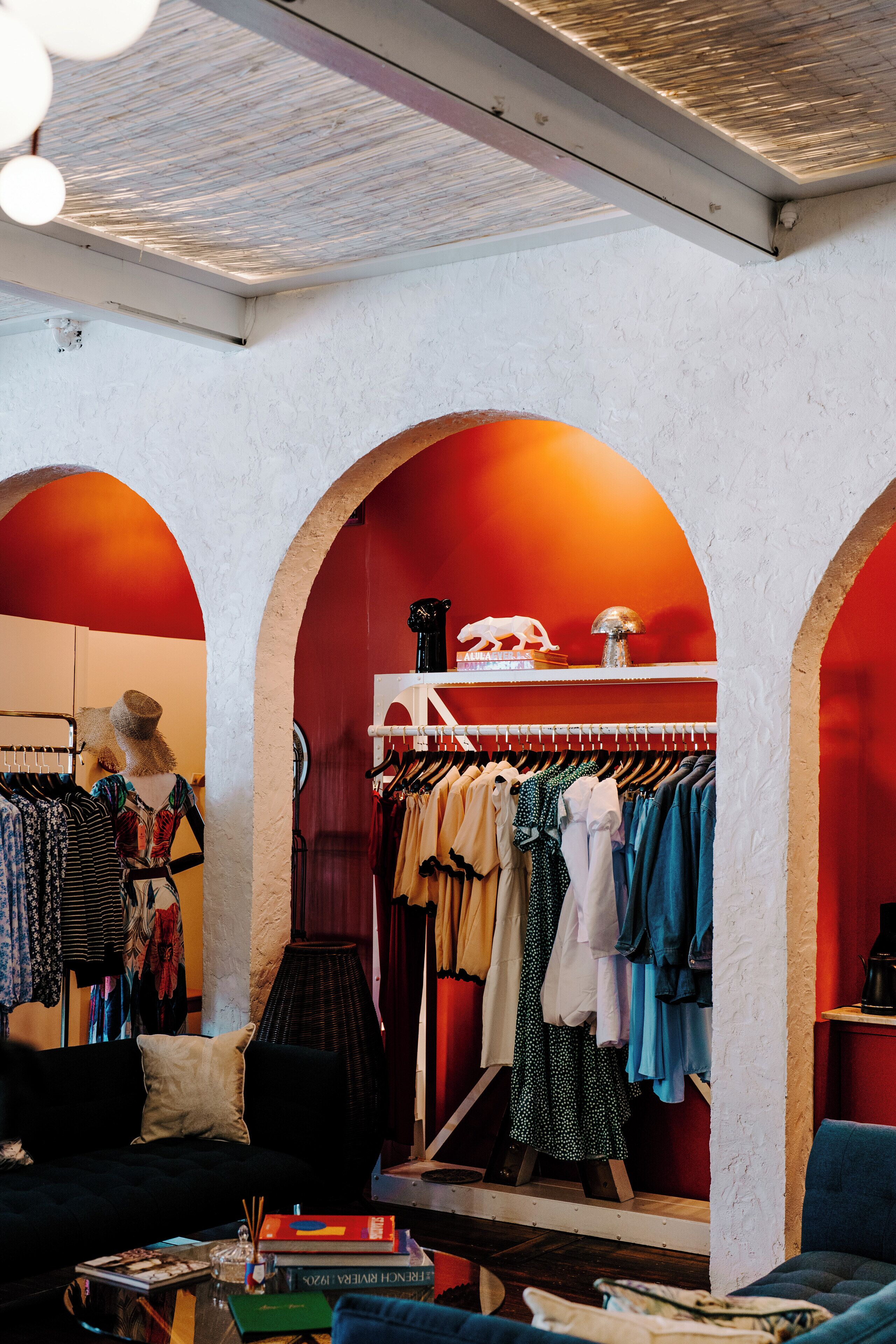 A boutique hotel interior with a clothing store, a sofa, and a coffee table.