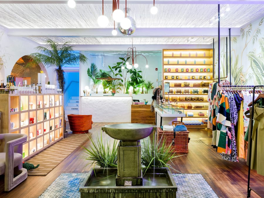Ein modernes Interieur mit einer zentralen Wasserspende, Regalen mit Produkten und einer Kleiderstange.