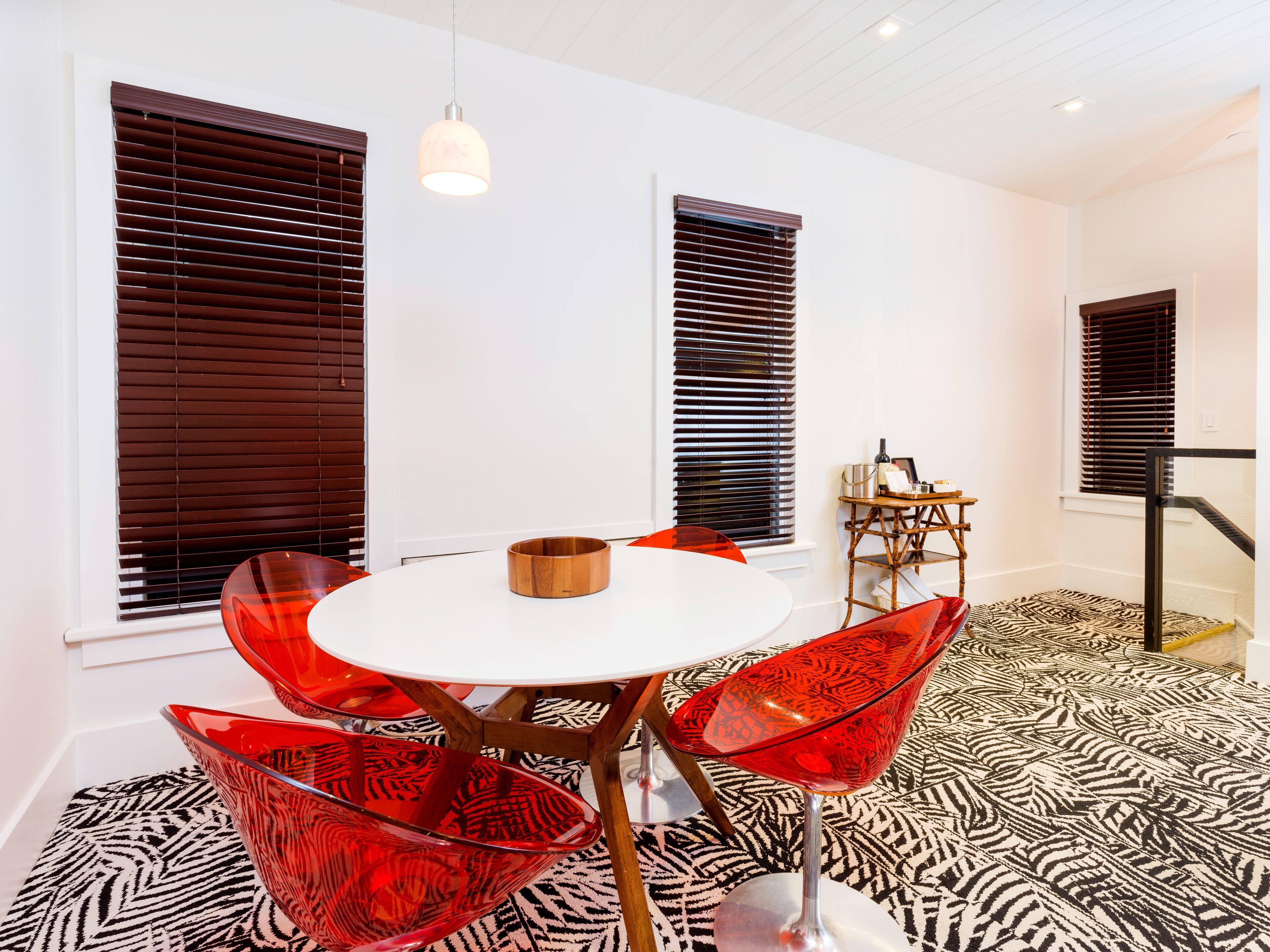 A modern dining area with a round table, red chairs, and a patterned floor.