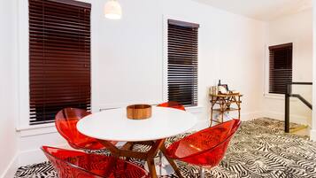 A modern dining area with a round table, red chairs, and a patterned floor.