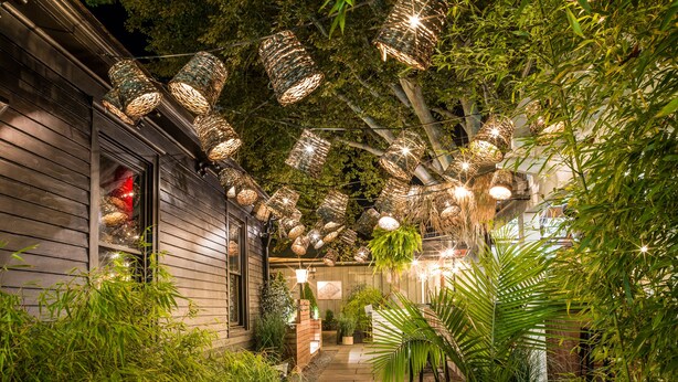 A pathway flanked by lush greenery and bamboo, leading to a building with a wooden exterior. - American Beech Hotel (Greenport)