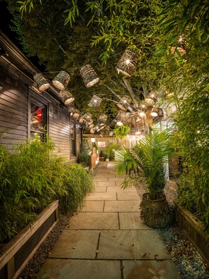 A pathway flanked by lush greenery and bamboo, leading to a building with a wooden exterior. - American Beech Hotel (Greenport)