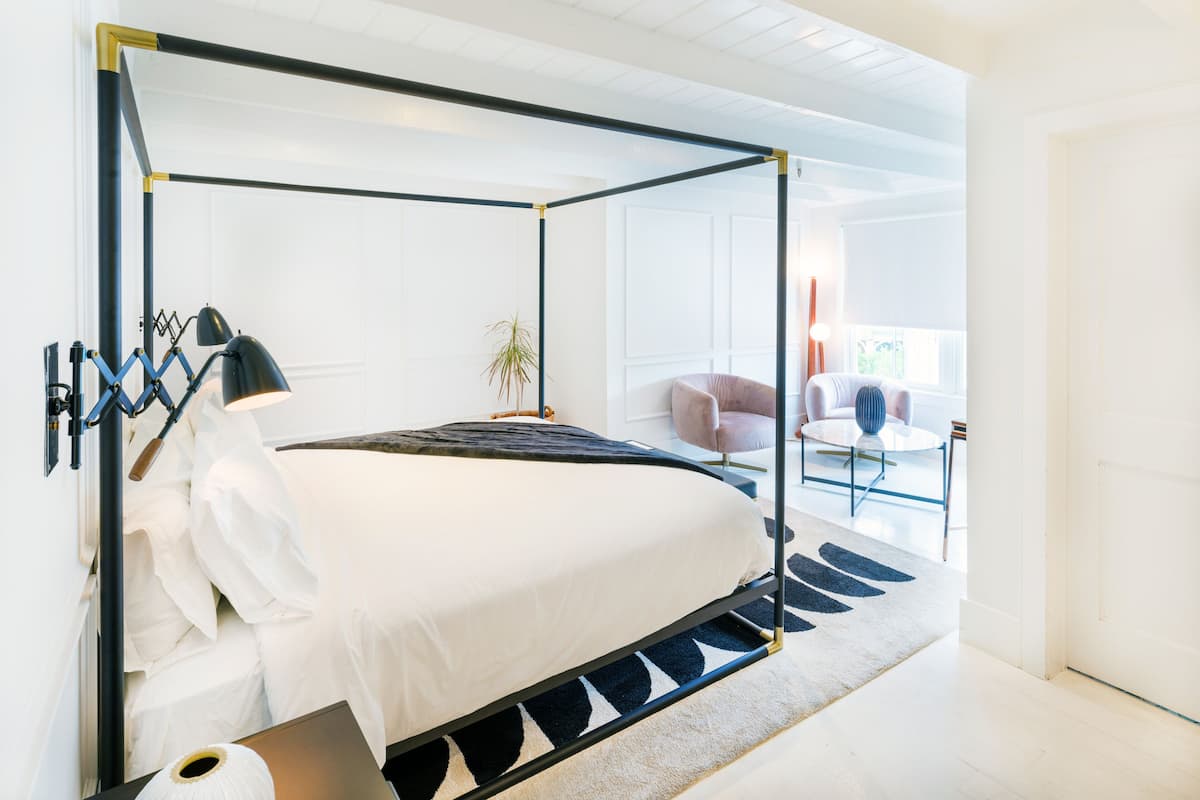 Une chambre à coucher moderne avec un lit à baldaquin, une lampe de chevet, une petite table et une chaise.