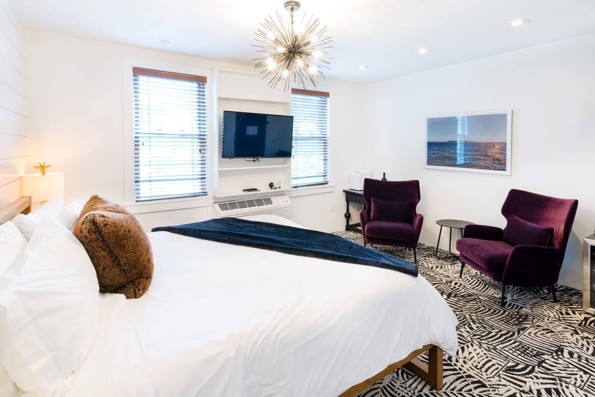 Une chambre d’hôtel moderne dotée d’un grand lit, d’un téléviseur à écran plat, d’un bureau, de deux chaises et d’un sol à motifs zébrés.