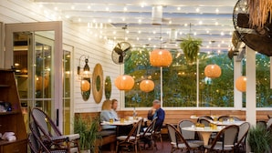 An outdoor dining area with tables and chairs, string lights, and hanging lanterns. - American Beech Hotel (Greenport)