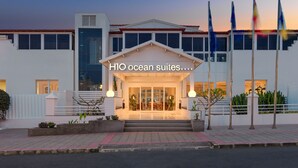 En modern hotellentrén med en skylt som visar texten ”H1O ocean suites”.