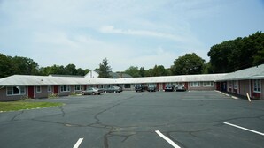 Un motel con un amplio estacionamiento y varias habitaciones.