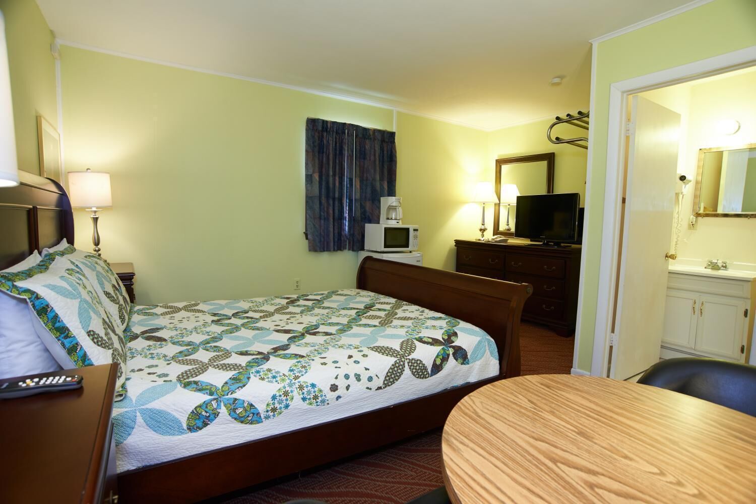 Hotelkamer met een bed, een bureau, een televisie, een magnetron en een badkamer zichtbaar door een geopende deur.