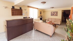 A spacious living area with a reception desk, a beige sofa, and a coffee table. - Domus Inn (Ioannina)