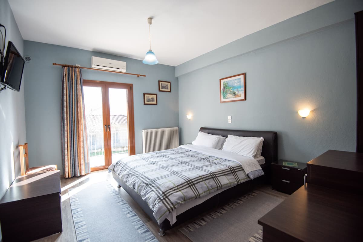 A bedroom with a bed, bedside tables, a TV, and a window with curtains.