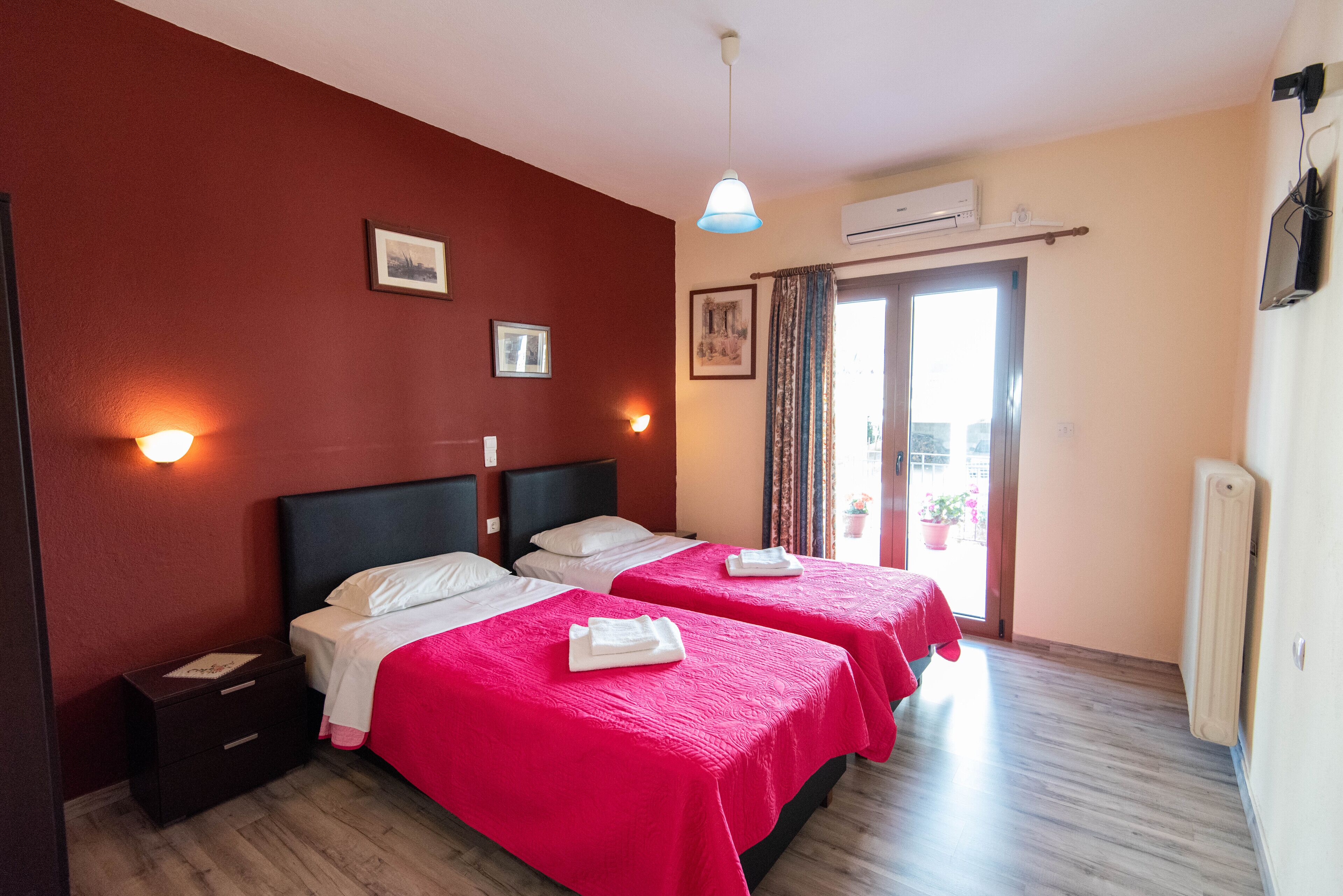 Een hotelkamer met twee bedden, een nachtkastje, een wandairconditioner en een raam met gordijnen.