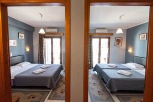 Reflejo en un espejo de una habitación de hotel con dos camas, una ventana con cortinas y una puerta que da a un balcón.