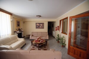 Una sala de estar con un sofá color beige, una mesa de centro con un centro de mesa floral y una chimenea.