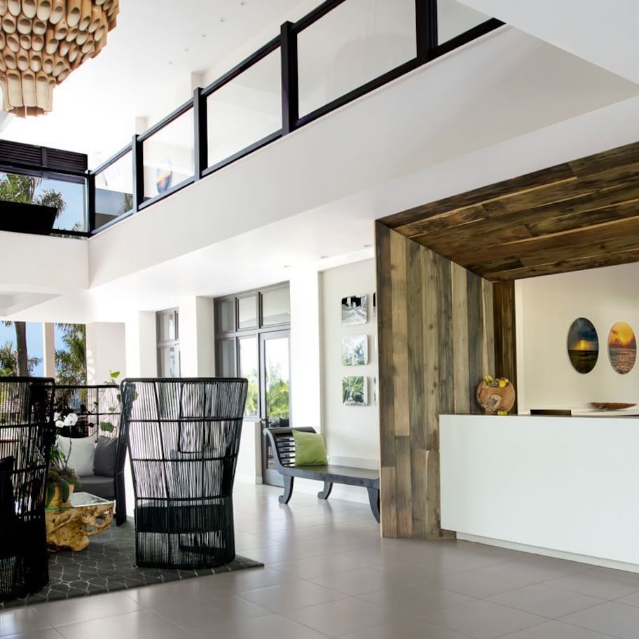 A spacious lobby with a high ceiling, a reception desk, and a view of the ocean.