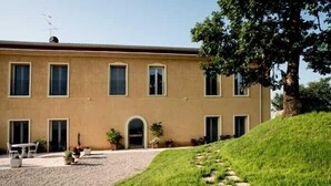 Un bâtiment à deux étages, doté d’un toit plat, d’une entrée centrale surmontée d’une arche et d’une allée de gravier menant à un espace verdoyant agrémenté d’un sentier en pierre.