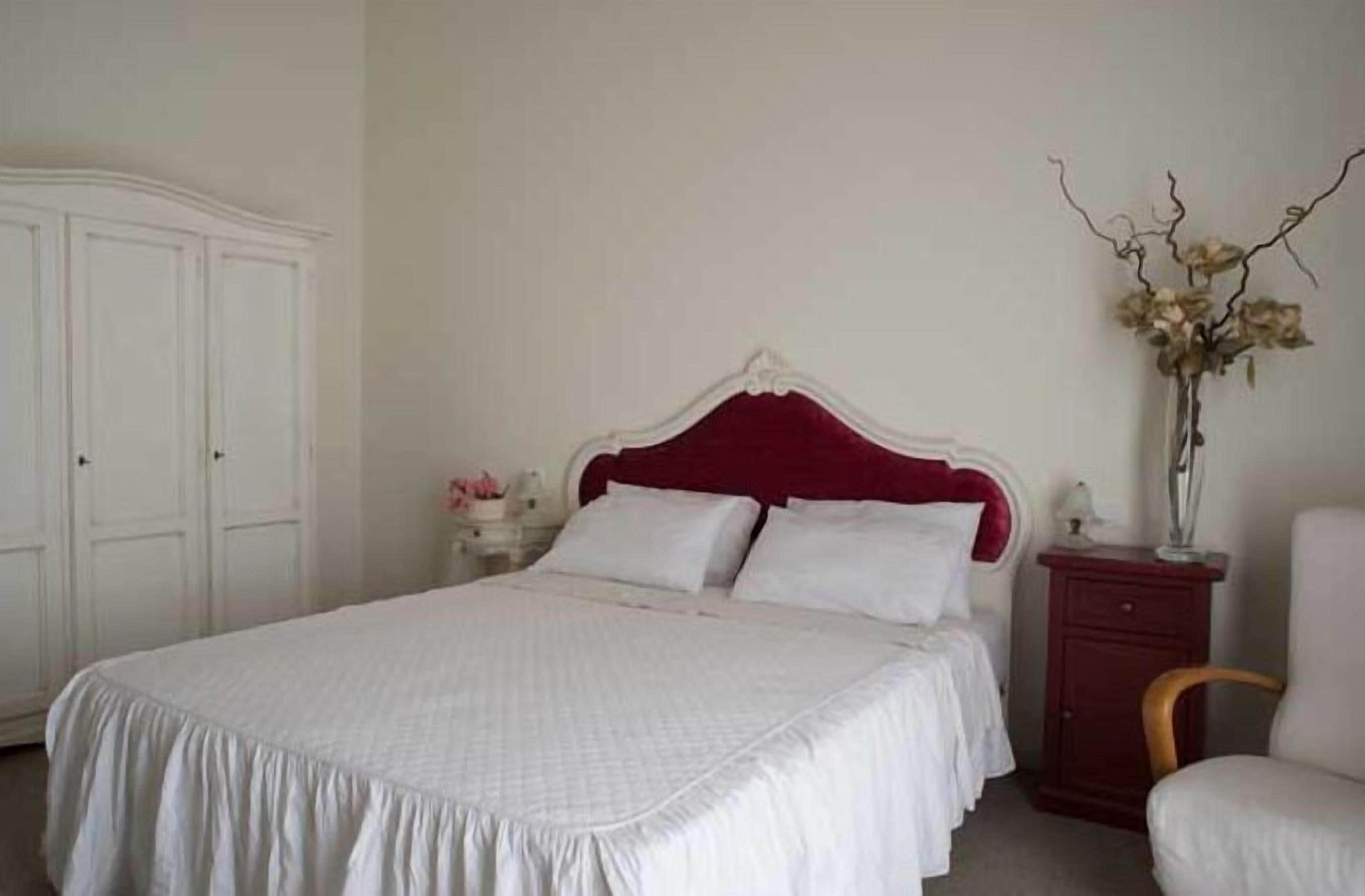 A neatly arranged bedroom with a large bed, a dresser, and a chair.
