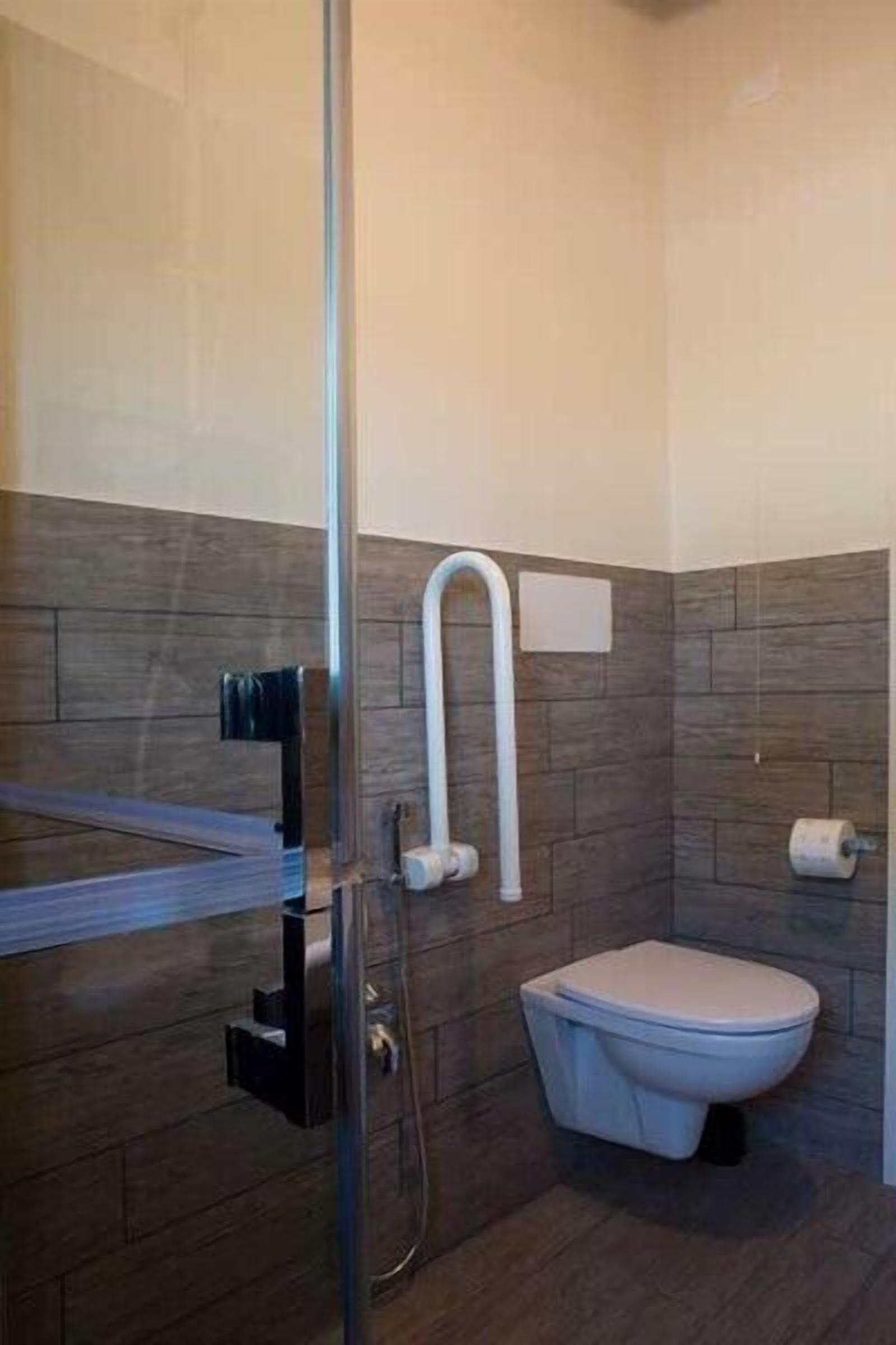 Un baño moderno con cabina de ducha de vidrio, inodoro y perchero para toallas.