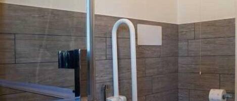 Un baño moderno con cabina de ducha de vidrio, inodoro y perchero para toallas.
