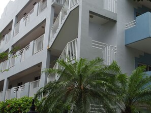 A multi-story building with balconies, a staircase, and palm trees in the foreground. - SoBe Apartments (Miami Beach)