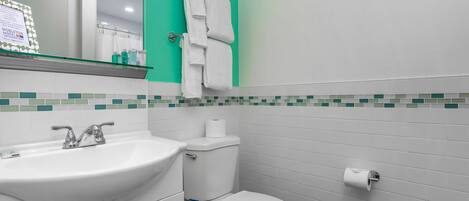A bathroom with a white sink, toilet, and a mirror above the sink.