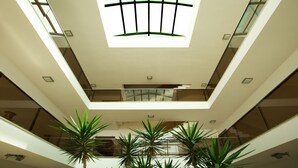 A modern interior with a central skylight, glass railings, and potted plants. - Lara Orkide Homes (Antalya)