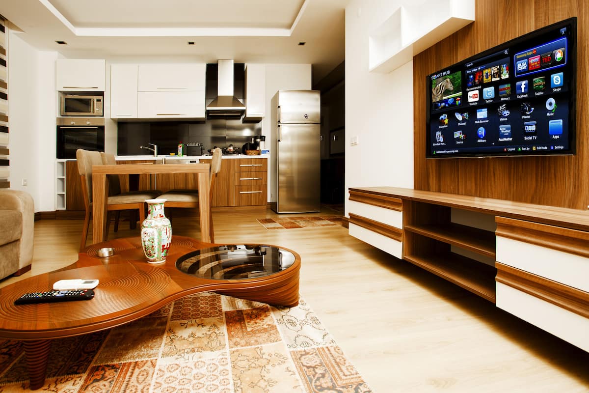 Uma cozinha moderna com televisão integrada, armários de madeira e uma área de refeições com uma mesa de centro em formato de guitarra.