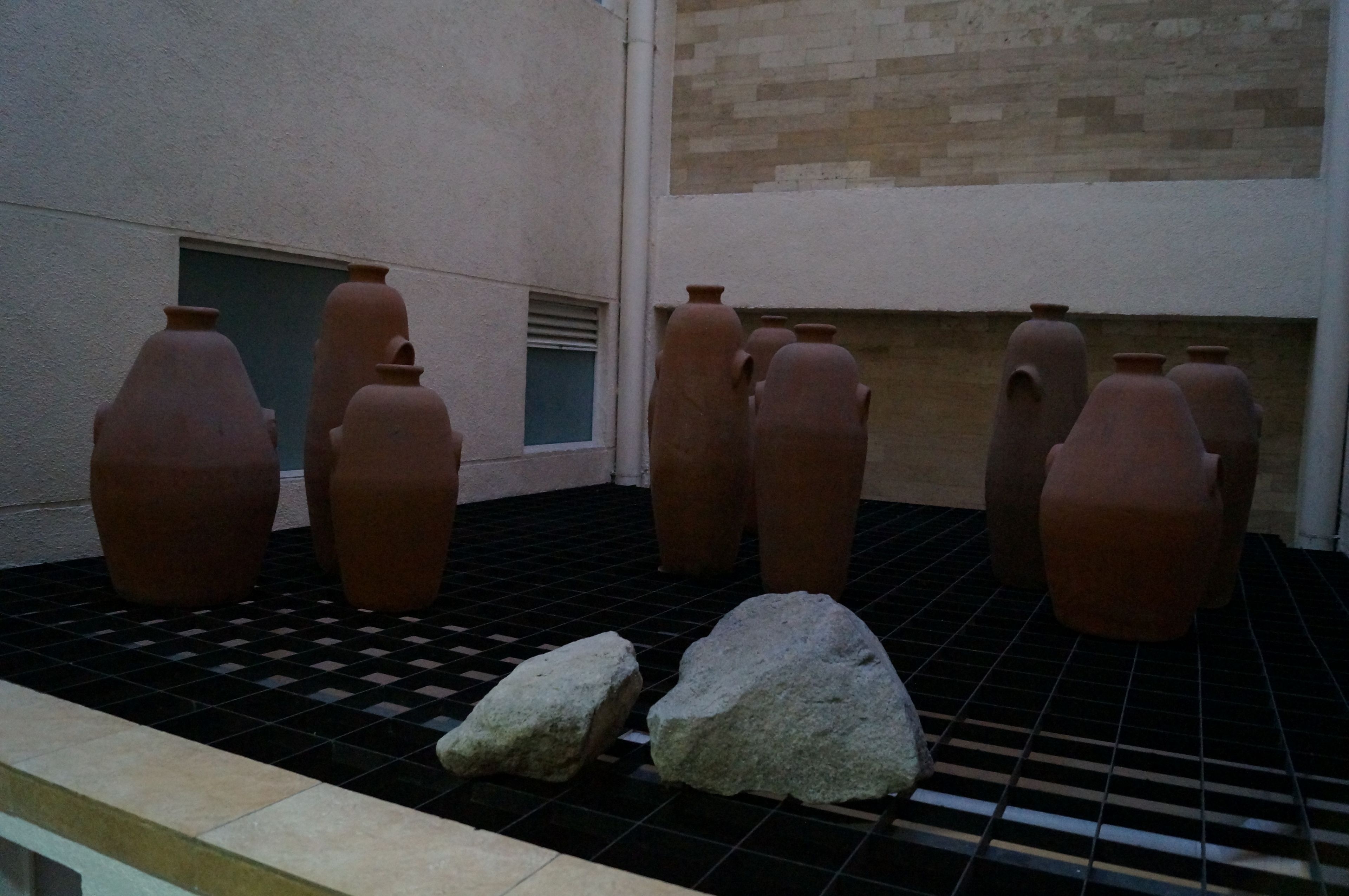 Terracotta pots arranged on a tiled floor in a courtyard.