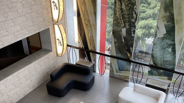 Un interior moderno con una zona de estar que incluye sofás y una mesa de centro, una pared de ladrillo y obras de arte en las paredes.