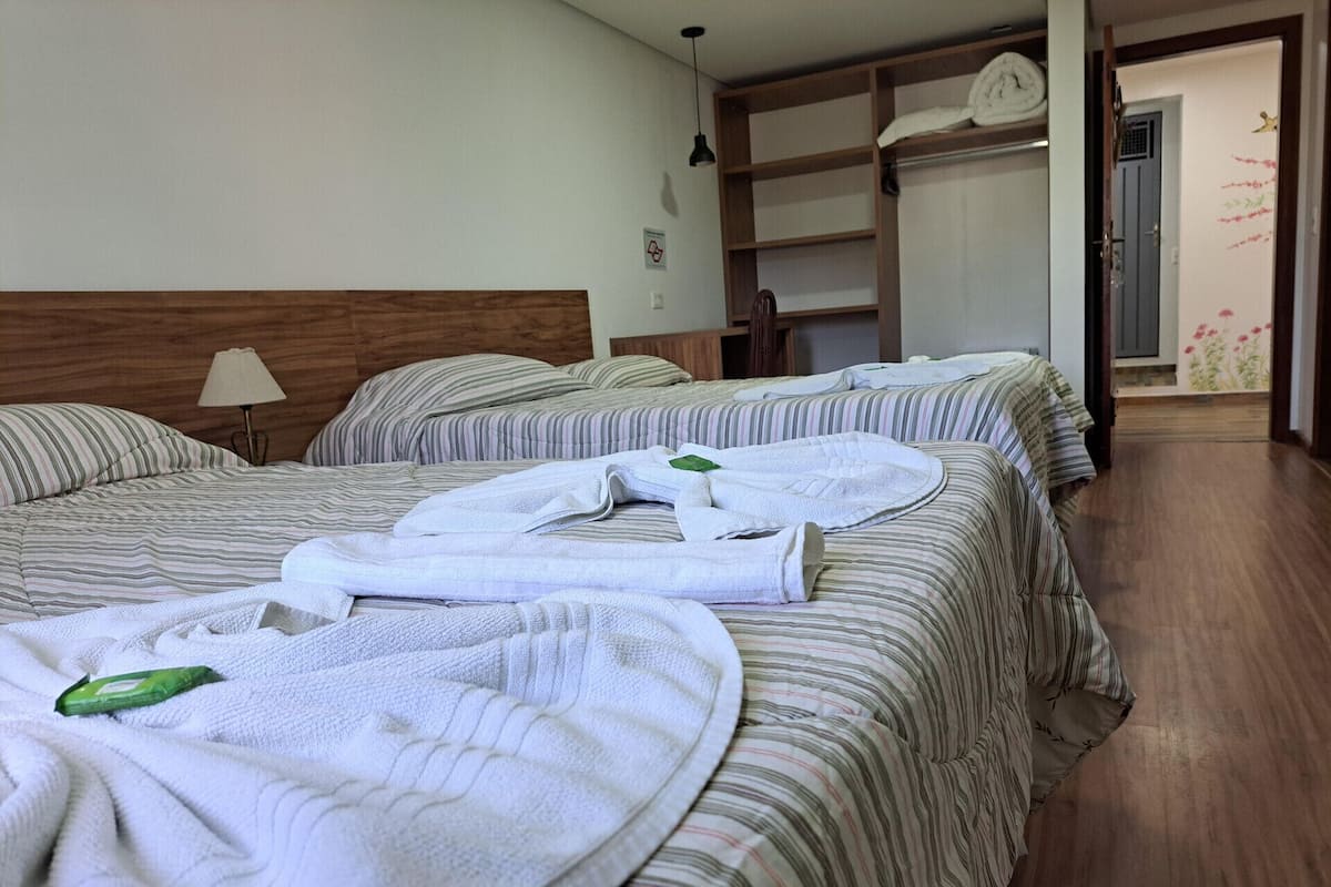 A hotel room with two beds, each with striped bedding and neatly folded towels.