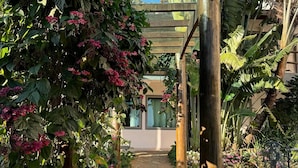 A stone pathway leading through a covered garden area with wooden posts and a pergola structure.