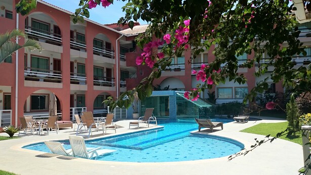 A hotel pool area with multiple lounge chairs and a water feature.