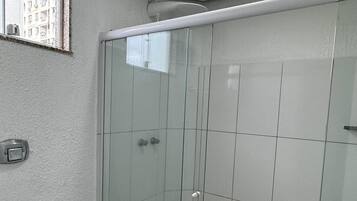 A bathroom with a toilet, a glass shower enclosure, and a window.