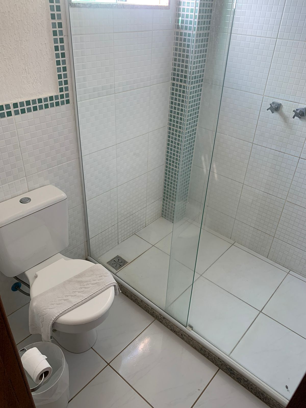 A bathroom with a toilet, a glass-enclosed shower, and tiled walls.