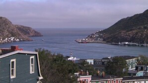 A coastal town with buildings along the shoreline, a view of the sea, and hills in the background. - Bond Guest House (St. John's)