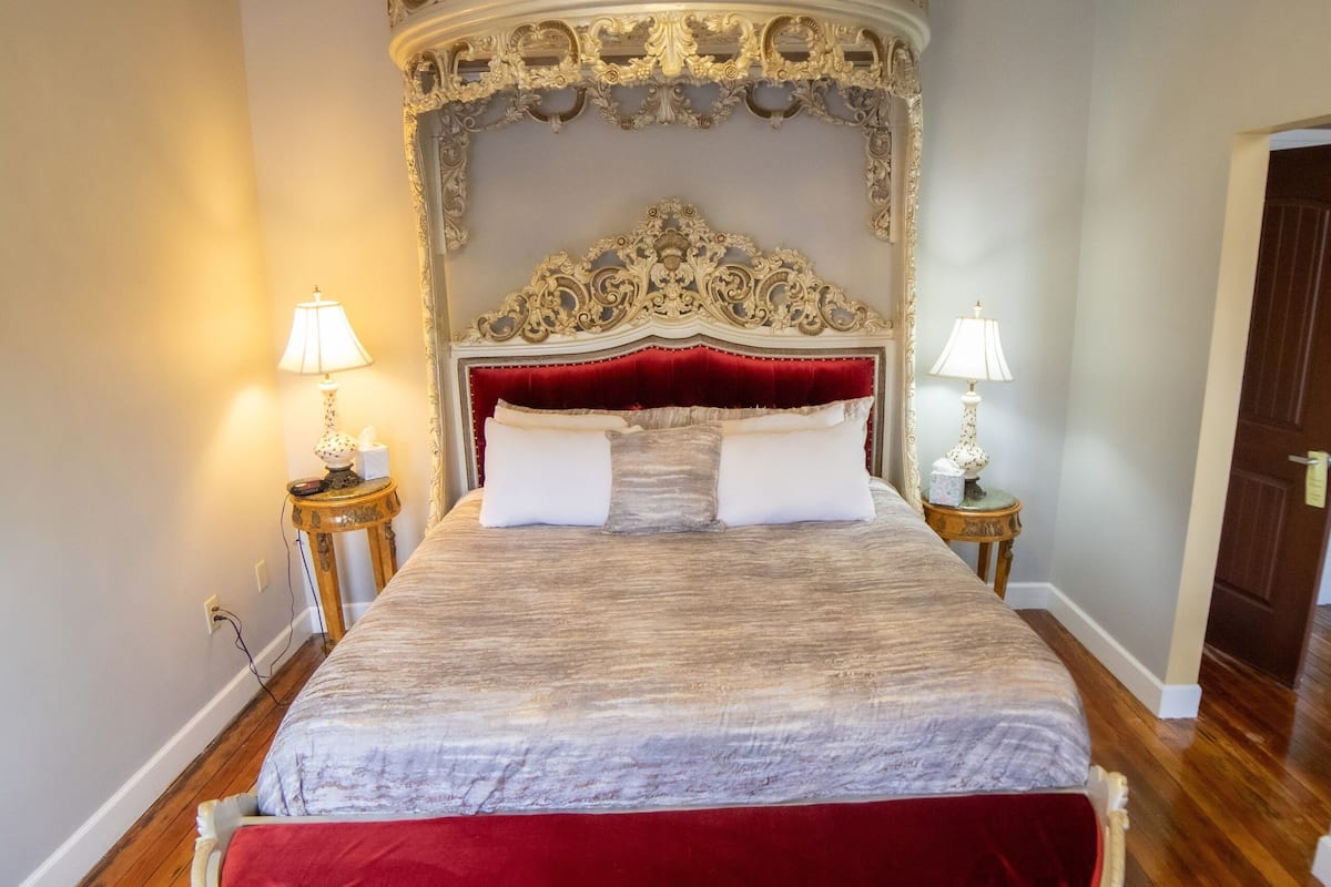 Ein großes Bett mit einem aufwendigen Kopfteil, zwei Nachttische mit Lampen und eine Chandelier.