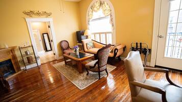 A living room with wooden flooring, a fireplace, a sofa, a coffee table, and a television.