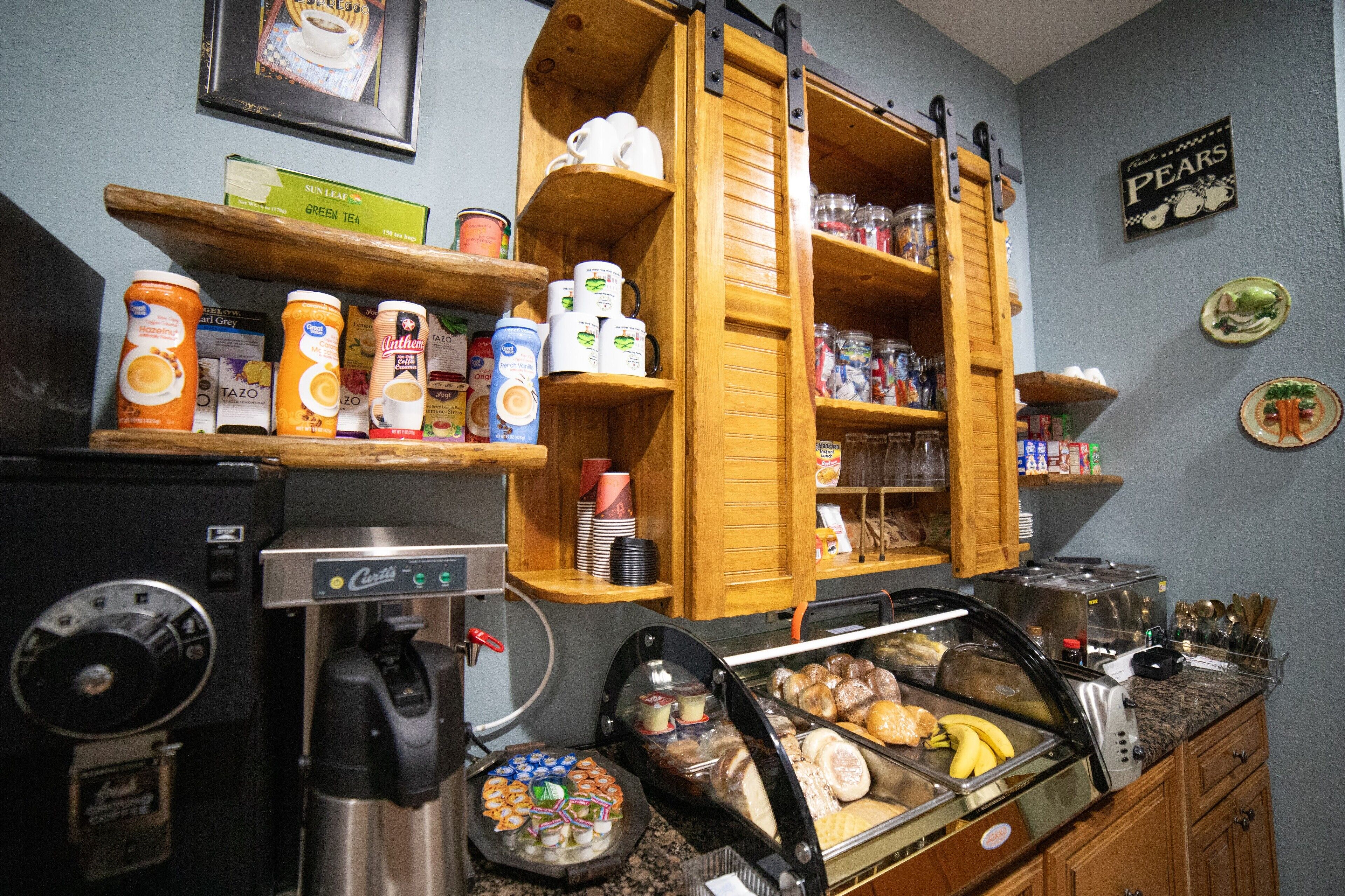 Un bufé de desayuno con diversos alimentos, una máquina de café y estantes con condimentos y utensilios.