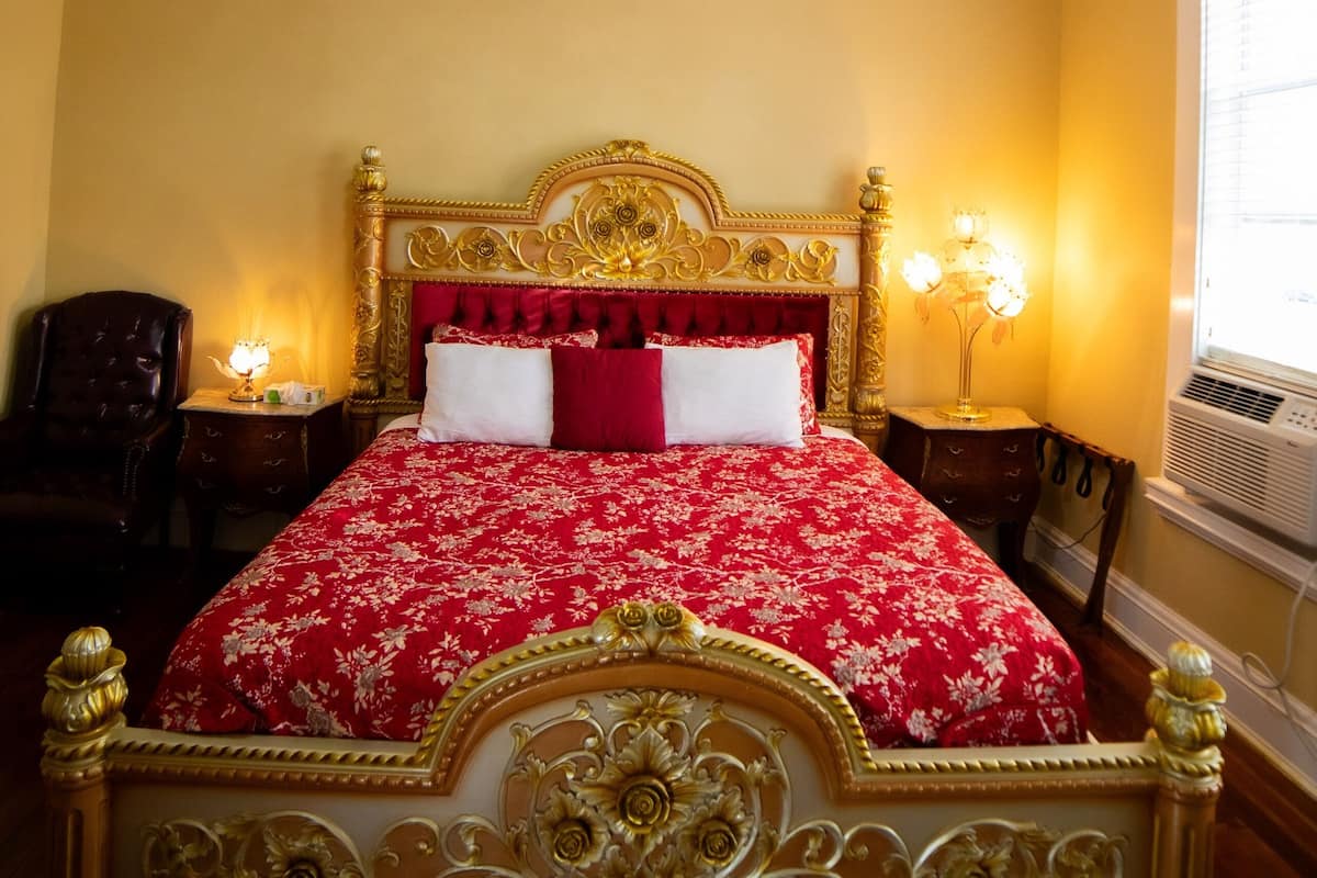Ein Schlafzimmer mit einem großen, verzierten Bett, einem Deckenventilator und zwei Nachttischlampen.