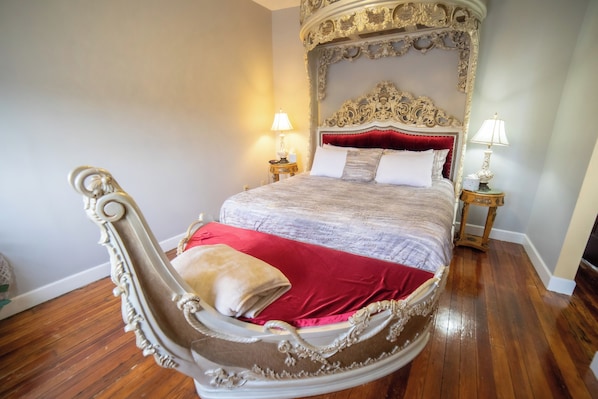 A four-poster bed with ornate carvings, red bedding, and two bedside lamps. - Oaak Tree Hotel (Arcadia)